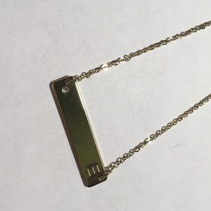 Gold colored necklace with a gem and letter E.